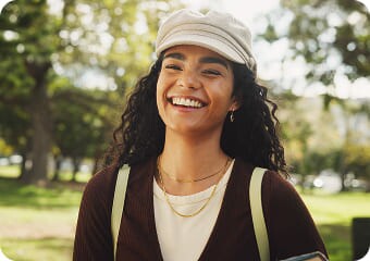 Mulher sorrindo ao ar livre, com uma mochila